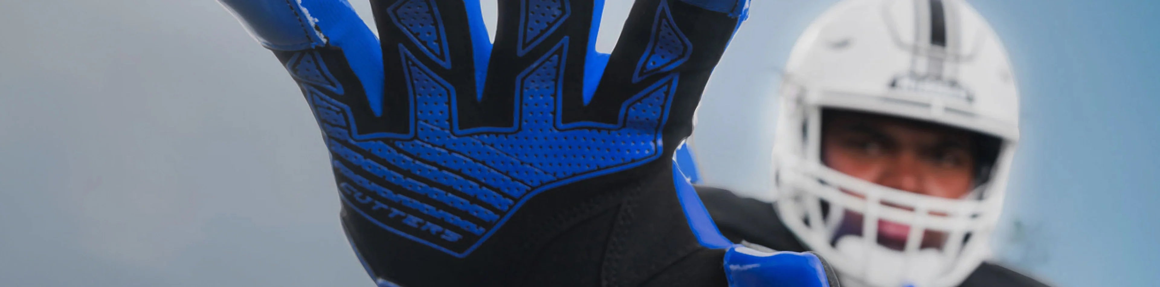 Header image for the 'Lineman Football Gloves' Collection by Cutters Sports. A football player in full gear extends a gloved hand toward the camera, showcasing durable blue-and-black gloves designed for linemen.