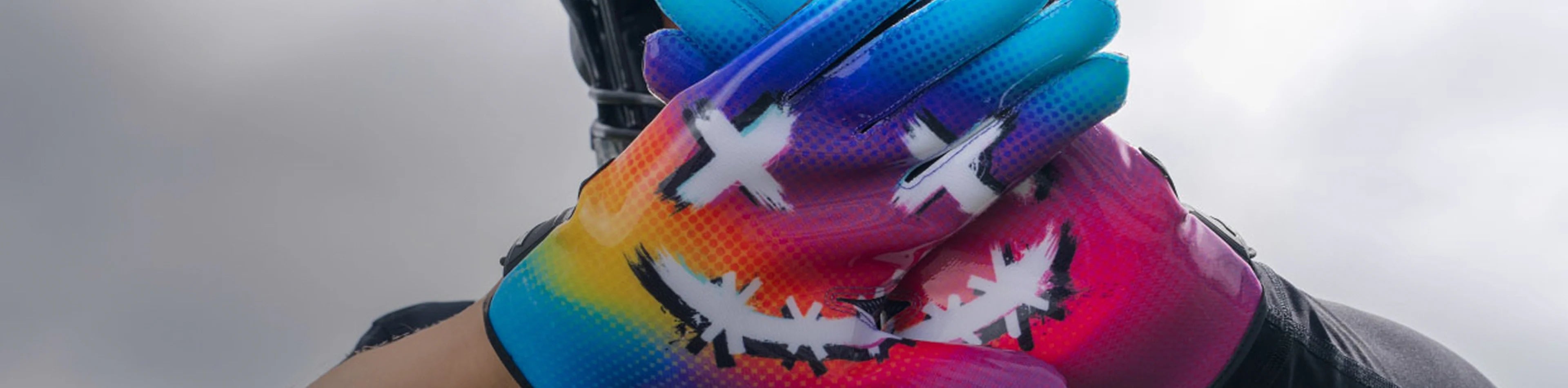 Header image for the 'Printed Football Gloves' Collection by Cutters Sports. A football player displays vibrant gloves with a multicolor gradient and graphic face design, featuring X eyes and a stitched smile pattern.