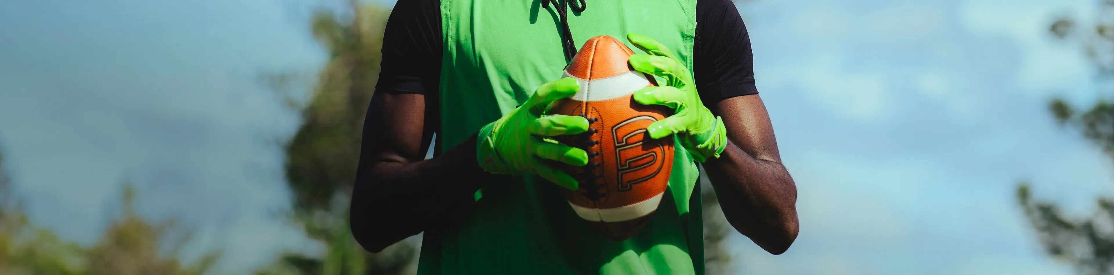 Header image for the 'Receiver Football Gloves' Collection by Cutters Sports. A football player in a green training vest grips a ball while wearing bright green receiver gloves, set against a sunny outdoor backdrop.