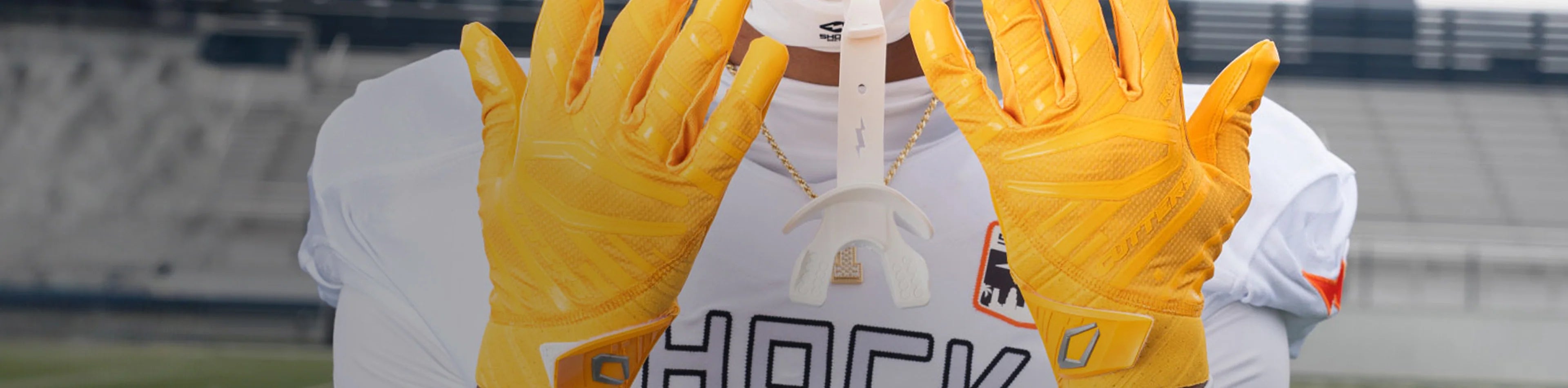 Gold Football Gloves' Collection by Cutters Sports. A football player showcases vibrant yellow receiver gloves on the field, with hands raised in front of a white jersey.