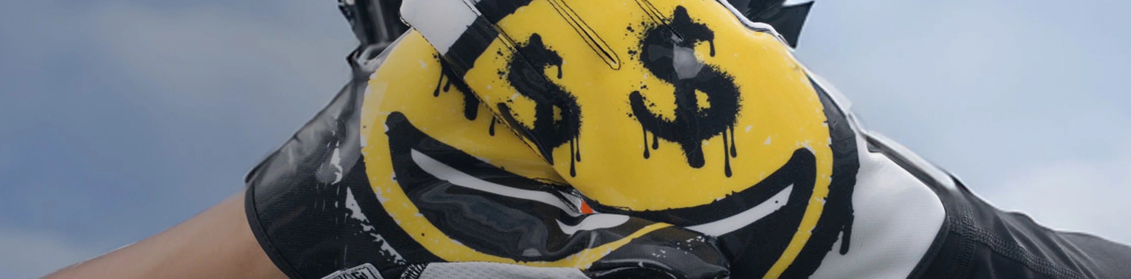 Header image for the 'Youth Football Gloves' Collection by Cutters Sports. A young athlete wears gloves featuring a bold yellow smiley face with dripping dollar sign eyes, held together to complete the graphic.