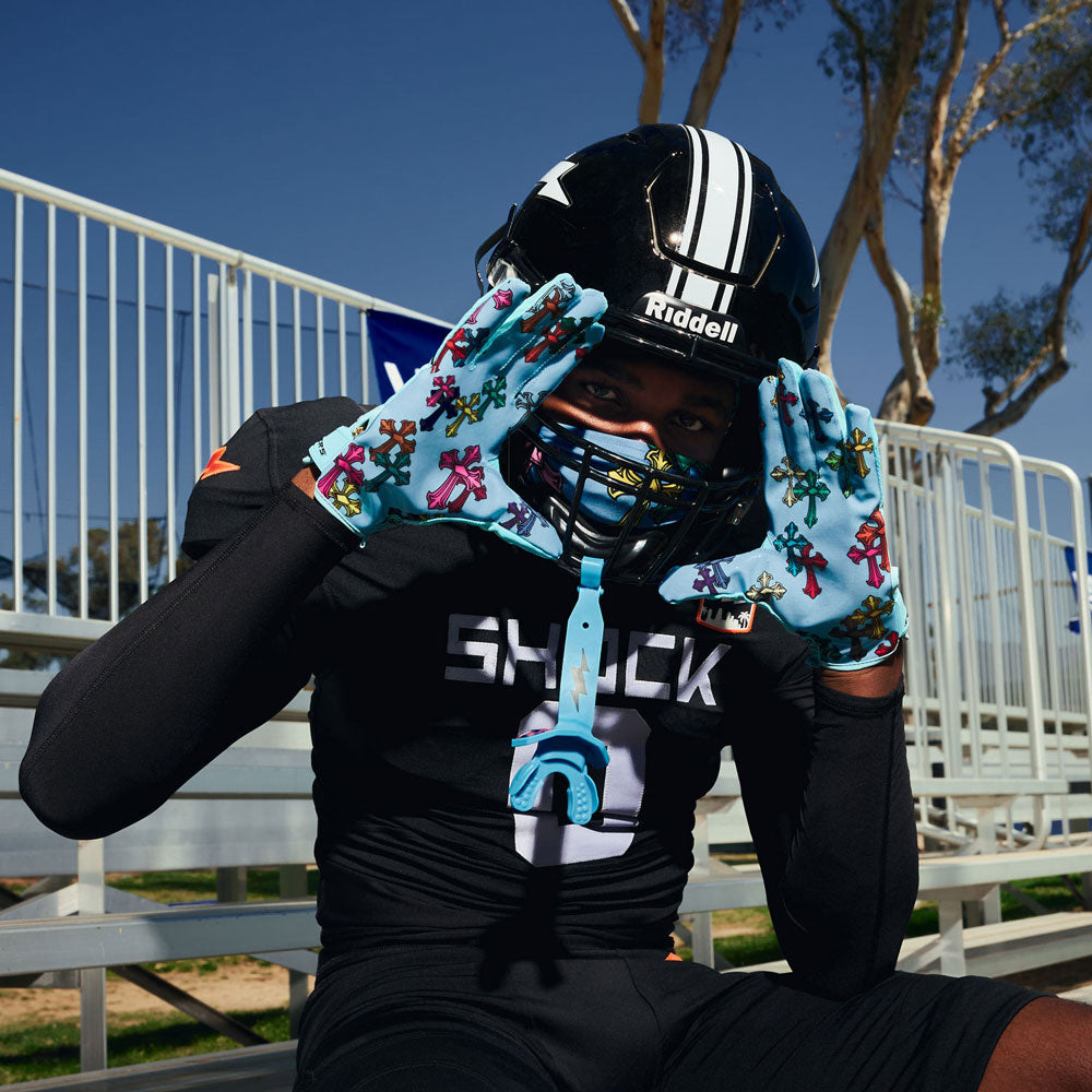 Football player framing his face with both hands wearing Blue Divine Drip Game Day Pro receiver gloves, with a matching blue Shock Doctor lipguard on his helmet